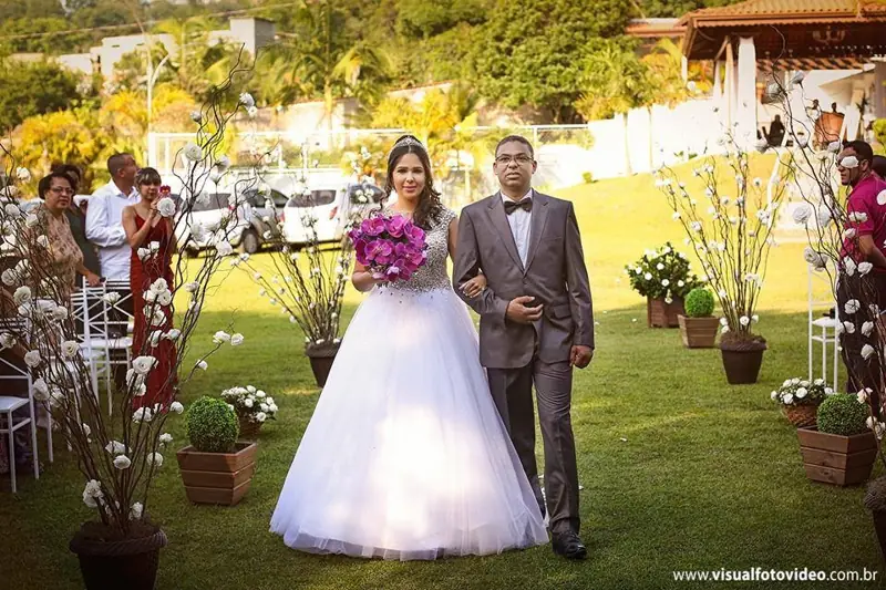 Noiva entrando com o pai no gramado durante a cerimônia