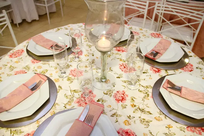 Mesa posta com louça branca, sousplat e flores
