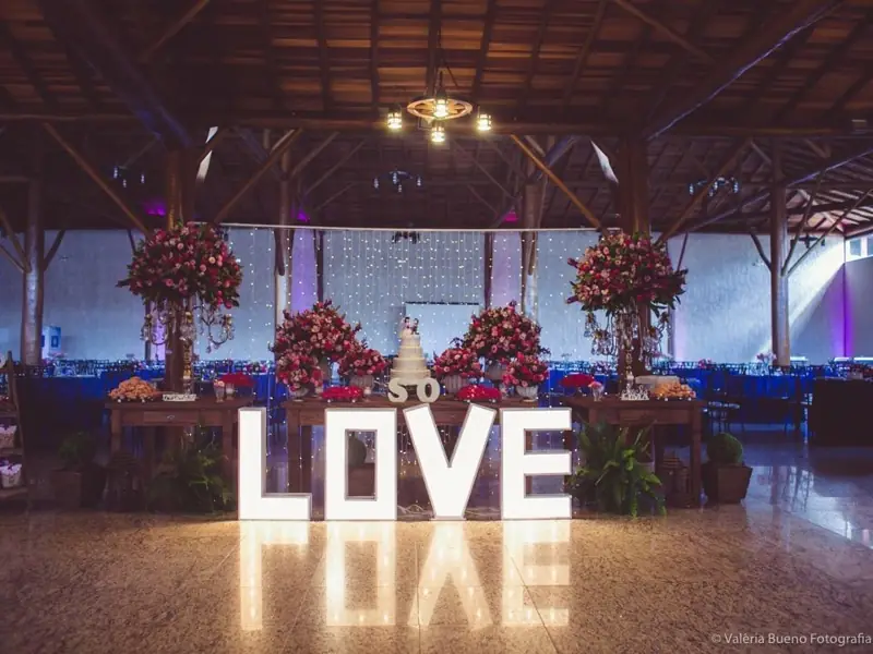 Salão com letreiro LOVE iluminado e mesas decoradas
