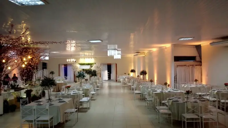 Salão Ouro montado com mesas redondas, árvore florida e luz quente